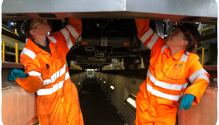 Two apprentices working underneath a train