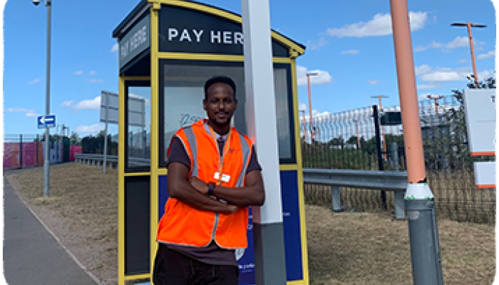 Daniel Kidane standing next to Coventry station railway sign.