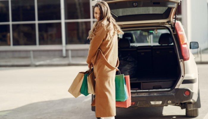 Woman with shopping bags standing by a car