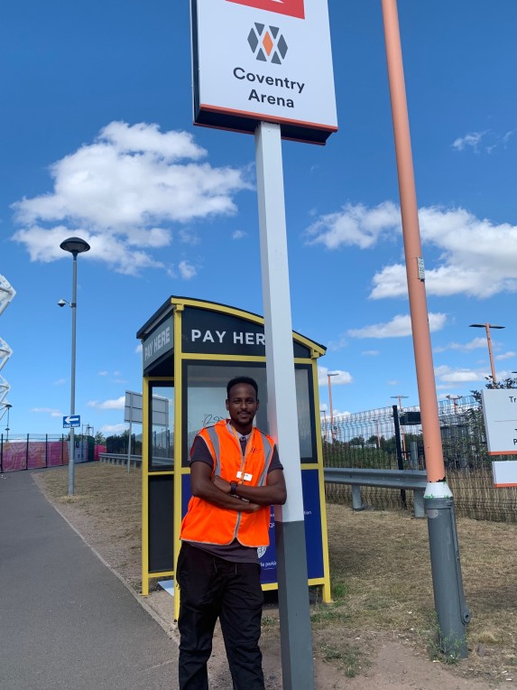 Daniel Kidane next to coventry station sign.